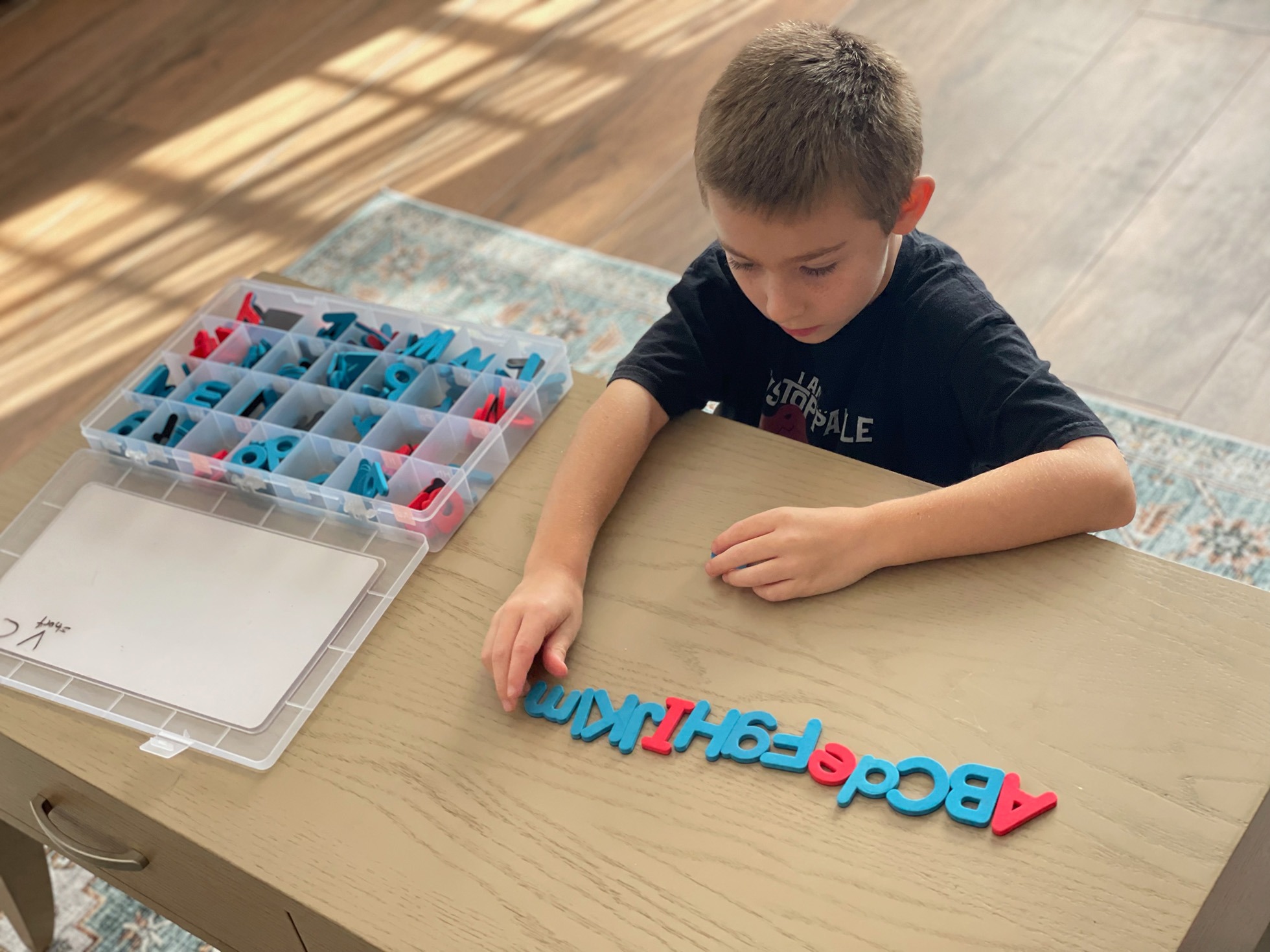A young boy creatively arranges colorful magnetic letters on a table, focusing intently as he spells out words.